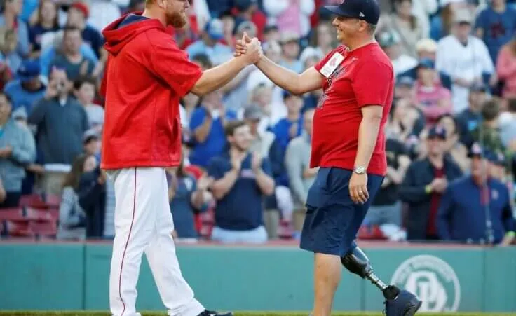 Boston Marathon bombing survivor J.P. Norden, right, of Stoneham, Mass., shakes hands with Boston Red Sox's Blaine Boyer after throwing out the ceremonial first pitch before a baseball game against the Kansas City Royals in Boston, Saturday, July 29, 2017. (AP Photo/Michael Dwyer)