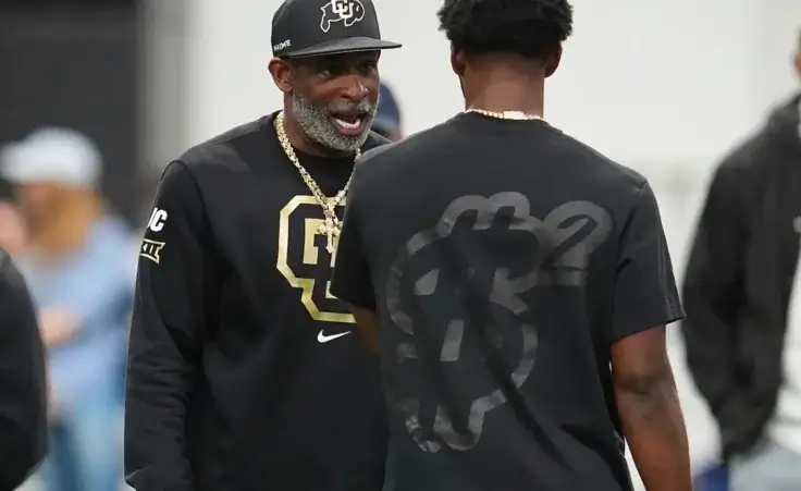 Colorado head coach Deion Sanders, left, talks with his son, quarterback Shedeur Sanders before passing drills at Colorado's NFL football pro day Friday, April 4, 2025, in Boulder, Colo. (AP Photo/David Zalubowski)