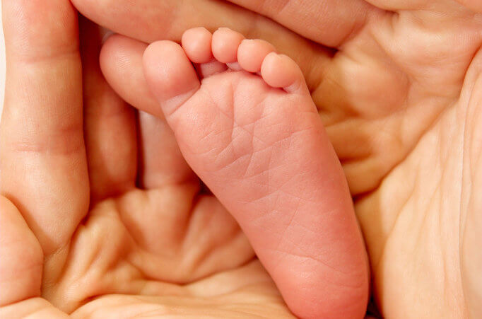 Adult hands holding the foot of a baby (Credit: Pawel Loj via Flickr)