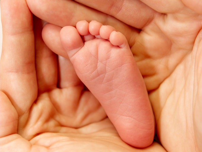 Adult hands holding the foot of a baby (Credit: Pawel Loj via Flickr)