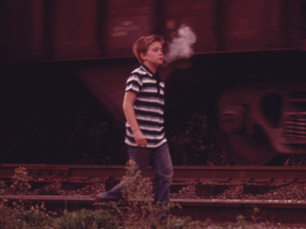 The cool morning air condenses a boy's breath as he walks along a coal car on his way to school in Cumberland, Kentucky in Harlan County 1974 (Credit: National Archives/Jack Corn)
