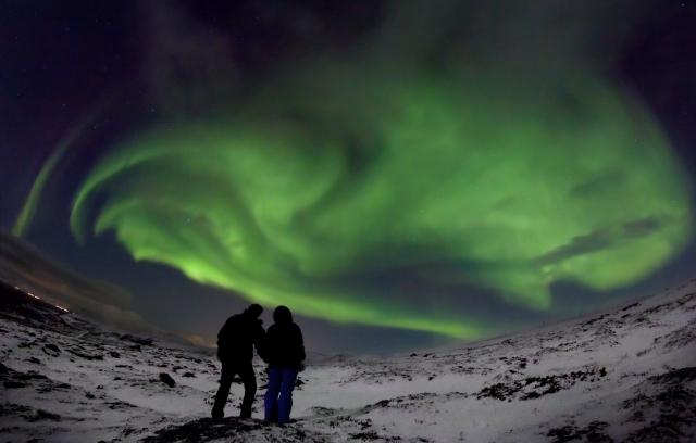 Two people under spectacular northern lights display, near Hammerfest, Norway(Credit: Reuters/Zbigniew Wantuch)