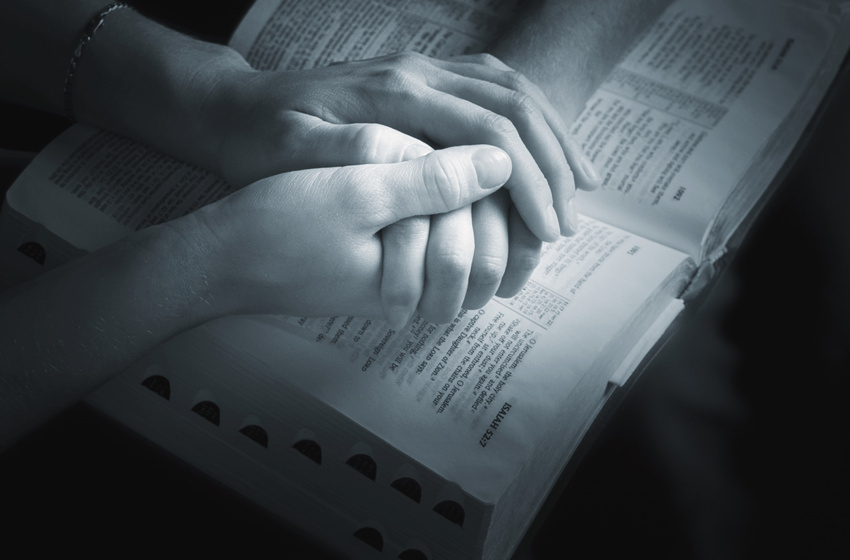 holding hands over the Bible (Credit: Vibe Images via Fotolia)