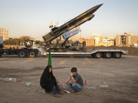 An Iranian couple rests as they sit in front of an Iranian-made Zelzal missile at a war exhibition held by Iran's revolutionary guard to mark the anniversary of the Iran-Iraq war, in southern Tehran, September 26, 2011 (Credit: Reuters/Morteza Nikoubazl)
