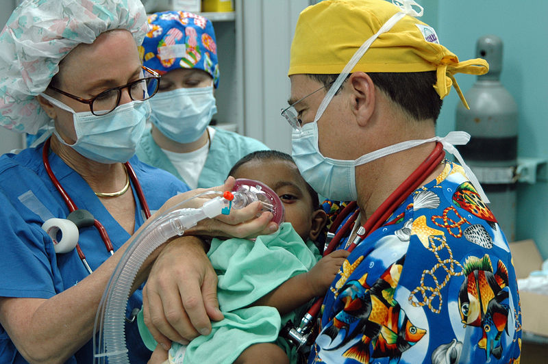 Chittagong, Bangladesh (July 2, 2006) – Operation Smile volunteers Janet Casabon Benowitz and Dr. Bill Pond anesthetize a young child before undergoing corrective plastic surgery on his cleft lip aboard U.S. Naval hospital ship USNS Mercy (T-AH 19), during the ship’s visit to provide humanitarian and civic assistance to the people of Bangladesh (Credit: US Navy/photo by Mass Communication Specialist Seaman Joseph Caballero)