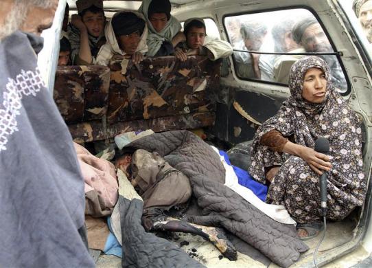 An Afghan woman is interviewed next to the body of a child killed by a rogue US soldier in Kandahar province, March 11, 2012 (Credit: Reuters/Ahmad Nadeem)