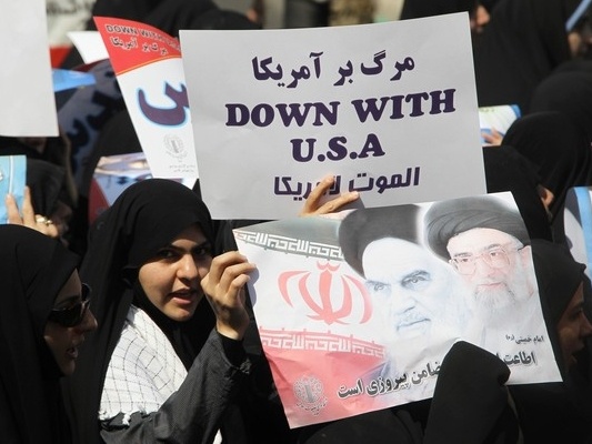 An Iranian student holds a picture of Supreme Leader Ayatollah Ali Khamenei (L) and Iran's Late Leader Ayatollah Ruhollah Khomeini during a rally outside the former U.S. embassy in Tehran (Credit: Reuters/Raheb Homavandi)