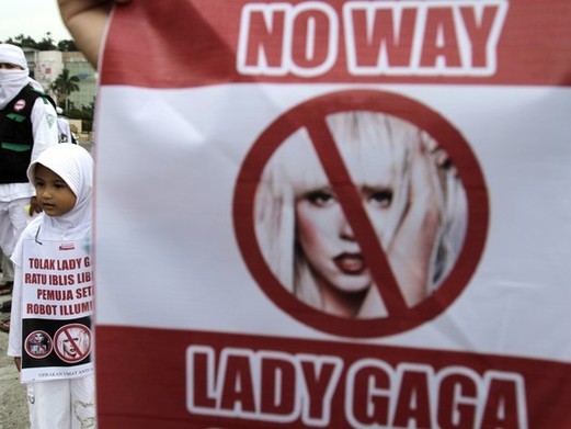 A child stands next to an anti-Lady Gaga banner in Jakarta April 29, 2012. Dozens of Muslim activists staged an anti-Lady Gaga rally against the concert by the American pop star which is planned to be held in Jakarta on June 3 (Credit Reuters/Supri)