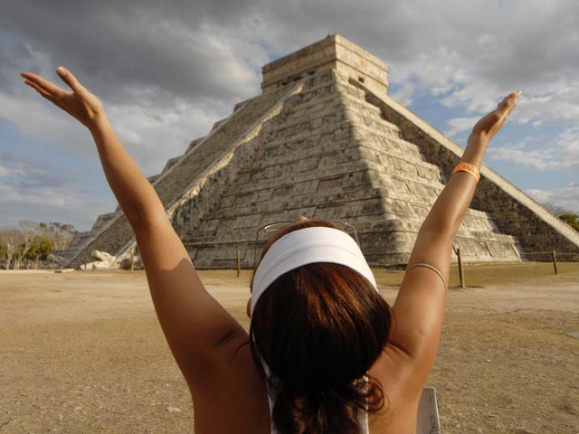 A woman raises her arms to receive energy from the sun at the Mayan pyramid El Castillo (The Castle), in Chichen Itza, in the southern state of Yucatan, Mexico March 21, 2009 (Credit: Reuters/Argely Salazar)