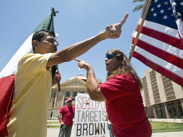 Andy Hernandez, carrying a Mexican flag, and Allison Culver, carrying an American flag, argue over Arizona’s immigration law outside the state capitol in Phoenix (Credit: Arizona Republic / Patrick Breen)
