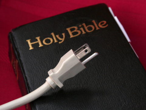 Connect with the power of God, a power cord laying across a Bible on a red cloth (Credit: thegarden via fotolia.com)