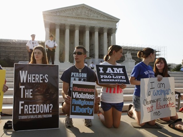 Protesters against the Obama administration's health-care law gather outside the Supreme Court in Washington, D.C. On the last day of its term, the court voted to uphold the law and its controversial individual mandate (Credit: Reuters / Jason Reed)