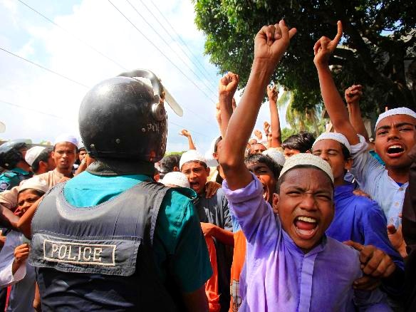 Bangladeshi Muslims chant slogans in front a policeman in a protest rally during a nationwide strike in Dhaka on Sunday, September 23. The day-long strike called by 12 Islamist groups are protesting against a US-made anti-Islam film and a cartoon published in a French weekly on Saturday that they say insults the Prophet Mohammad, local media reported (Credit: Reuters / Andrew Biraj)