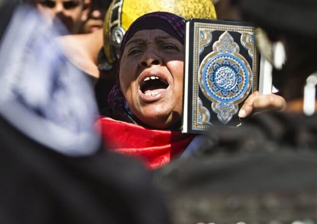A Palestinian woman shouts as she hold a Koran during demonstrations denouncing a U.S.-made film that mocks the Prophet Mohammed, after Friday prayers near Damascus Gate outside Jerusalem's Old City September 14, 2012 (Credit: Reuters / Nir Elias)