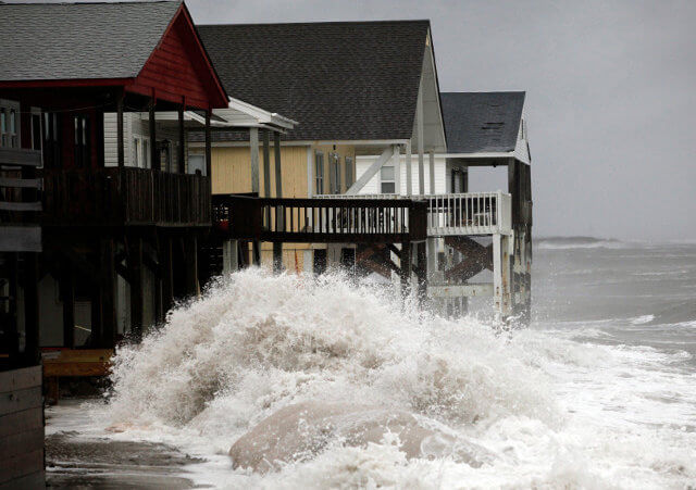 A wave crashes over the protecting sandbags in front of the houses on the east side of Ocean Isle Beach during Hurricane Sandy in Ocean Isle Beach, North Carolina, October 27, 2012 (Credit: Reuters/Randall Hill)