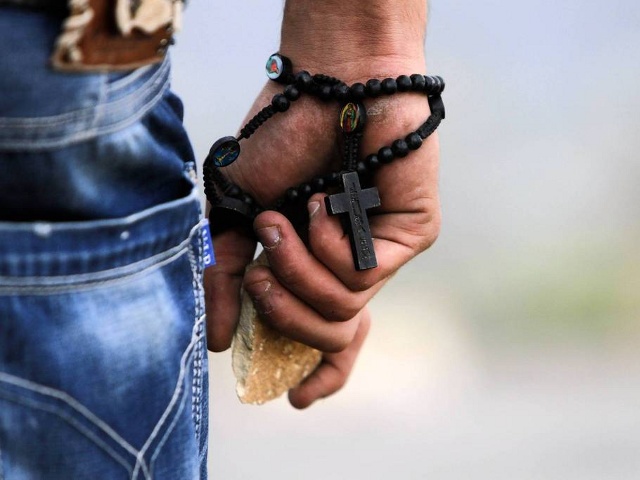 A Palestinian demonstrator wearing a rosary holds a stone during minor clashes with Israeli troops in protest against Israel's military operation in the Gaza Strip, in the West Bank village of Bir Zeit, near Ramallah, November 19, 2012 (Credit: Reuters/Mohamad Torokman)