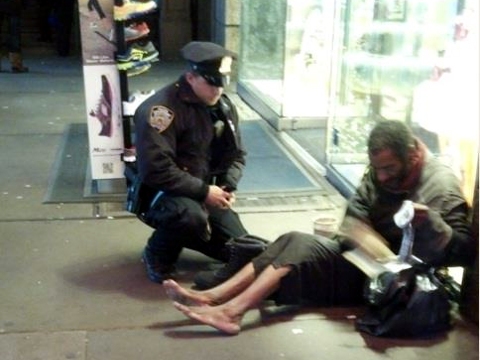 Officer Lawrence DePrimo bought new boots for a homeless man he encountered in Times Square; here he is giving them to the shoeless man (Credit: Jennifer Foster via Facebook)