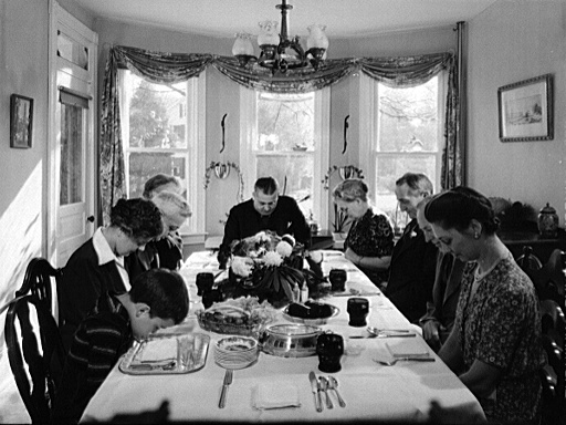 Saying grace before carving the turkey at Thanksgiving dinner in the home of Earle Landis in Neffsville, Pennsylvania (Credit: Marjory Collins / Farm Security Administration)