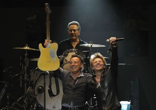 Singer Bruce Springsteen performs with Jon Bon Jovi (R) and drummer Max Weingberg during the