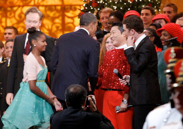 President Barack Obama shakes hands with South Korean musician Psy next to host Conan O'Brien, and performer Scotty McCreery during the