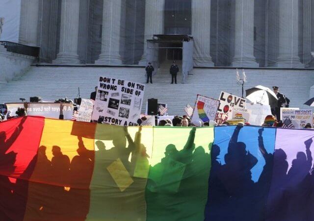 Defense of Marriage Act and Proposition 8 protesters are shadowed by a rainbow banner in front of the U.S. Supreme Court in Washington, March 26, 2013 (Credit: Reuters/Jonathan Ernst)