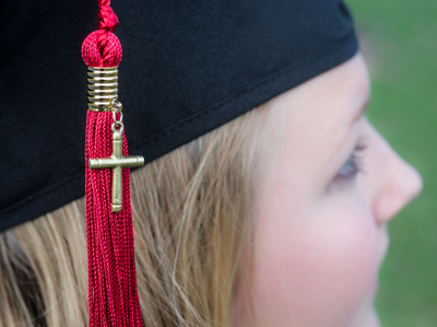 A young female graduate with a cross on her red tassel (Credit: Image 1:27 Photography via Lightstock)