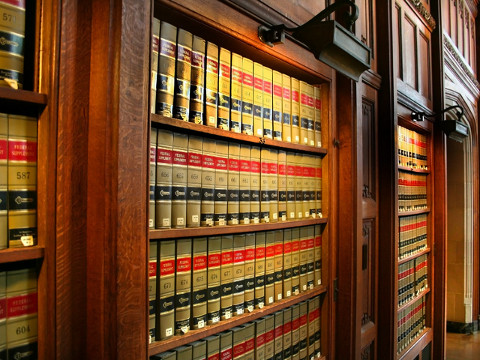 A bookcase with spotlight on legal tomes in a law library, representing the Supreme Court justices and their upcoming decision on DOMA and Prop 8 (Credit: SNEHIT via Fotolia)