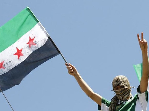 A Syrian refugee waves a Syrian Independence flag during a protest against Syria's President Bashar al-Assad at Yayladagi refugee camp in Hatay province on the Turkish-Syrian border (Credit Umit Bektas/Reuters)