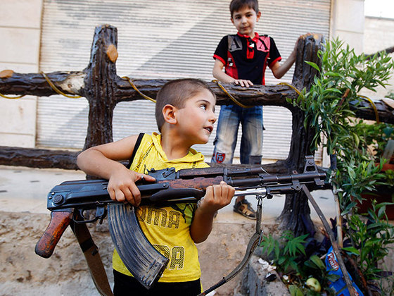 A boy plays with an AK-47 rifle owned by his father in Azaz, a small town north of Aleppo (Credit: Reuters/Goran Tomasevic)
