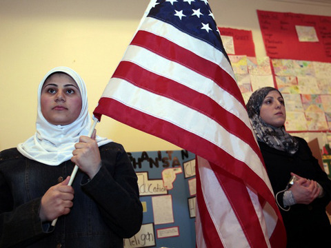A young Muslim American female student holds the U.S. flag during a Children of the World student pageant at the Islamic Center of America in Dearborn, Michigan (Credit: Reuters/Rebecca Cook)