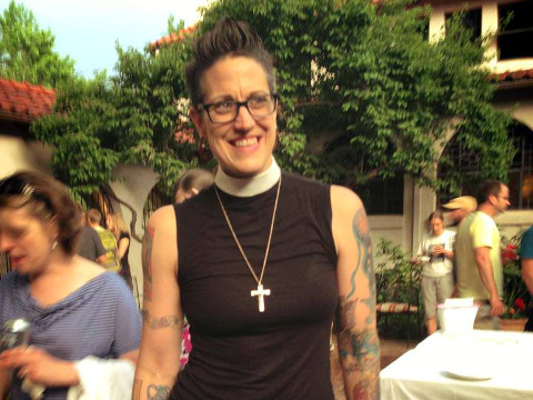 Nadia Bolz-Weber poses in a church courtyard for a photo wearing a cross and a new style clery shirt and collar for women (Credit: Nadia Bolz-Weber via Facebook)