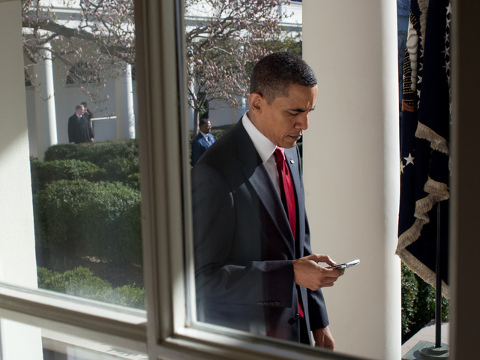 President Barack Obama checks his BlackBerry as he walks along the Colonnade to the Oval Office, March 18, 2010 (Credit: White House/Pete Souza)