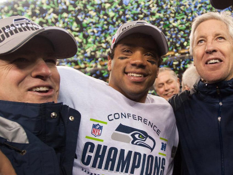 Russell Wilson (C), quarterback for the Seattle Seahawsk, celebrates victory in the 2014 NFC Championship game in Seattle with general manager, John Schneider (L), and coach Pete Carroll (R), in Seattle, January 19, 2014 (Credit: Seattle Seahawks/Rod Mar)