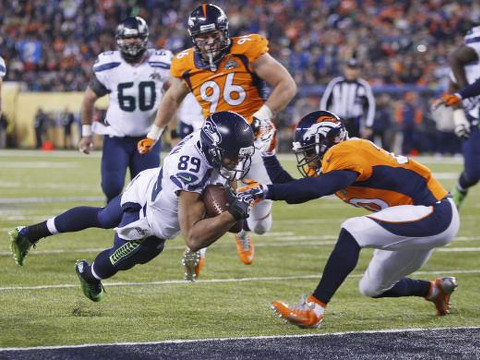 Seattle Seahawks wide receiver Doug Baldwin dives into the end zone for a touchdown past Denver Broncos free safety Mike Adams during the fourth quarter in the NFL Super Bowl XLVIII football game in East Rutherford, New Jersey, February 2, 2014. (Credit: Reuters/Carlo Allegri)