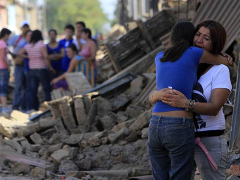 Residents lending each other support outside a destroyed building in Talca, 300km south of Santiago, Chile (Credit: Reuters/Victor Ruiz Caballero)