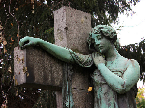 A stone statue of a woman leaning against a cross found in the Lutheran Georgen Parochial cemetery in central district Mitte of Berlin (Credit: Astra Nilsson via Flickr)
