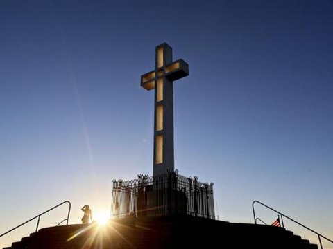 People gather in the late evening sun around the massive cross sitting atop the Mt. Soledad War Memorial in La Jolla, California on December 12, 2013 (Credit: Reuters/Sandy Huffaker)