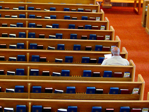 A man sits alone in a pew in a Presbyterian church as he awaits the start of a memorial service, September 8, 2012 (Credit: Quinn Dombrowski via Flickr)