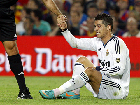Real Madrid's Cristiano Ronaldo grimaces as he is helped up by the referee after falling to the ground during their Spanish first division soccer match against Barcelona at Nou Camp stadium in Barcelona, October 7, 2012 (Credit: Reuters/Albert Gea)