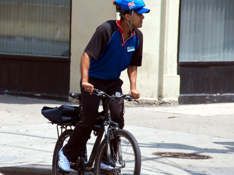 A Dominos delivery guy on the Upper West Side of Manhattan makes a delivery on his bike (Credit: Ed Yourdon via Flickr)