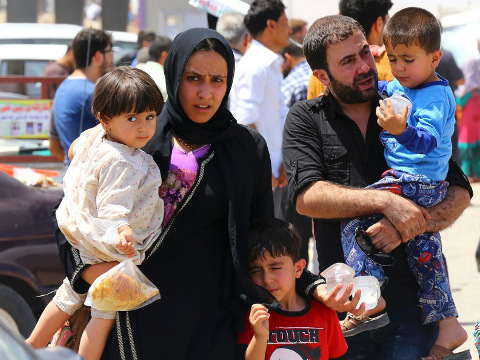 A family fleeing the violence in the Iraqi city of Mosul, after insurgents believed to be part of the Islamic State of Iraq and Syria (ISIS) seized the city, waits at a checkpoint in outskirts of Arbil, in Iraq's Kurdistan region, June 10, 2014. (Credit: Reuters/Stringer)