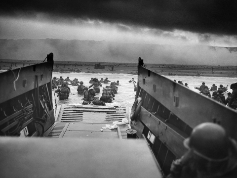 American troops of Company E, 16th Infantry, 1st Infantry Division spring from the ramp of a U.S. Coast Guard landing craft from the U.S. Coast Guard-manned USS Samuel Chase to wade those last perilous yards to Omaha beach of Normandy. Enemy fire will cut some of them down. Their taxi will pull itself off the sands and dash back to a Coast Guard manned transport for more passengers. The photo was taken by Robert F. Sargent, a United States Coast Guard chief petty officer (Credit: US Coast Guard/Robert F. Sargent, CPhoM, USCG)