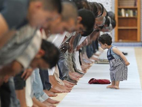 A child walks near members of the Muslim community attending midday prayers at Strasbourg Grand Mosque in Strasbourg on the first day of Ramadan July 9, 2013 (Credit: Reuters/Vincent Kessler)