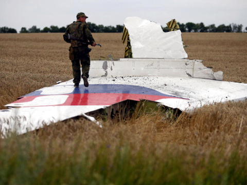 An armed pro-Russian separatist stands on part of the wreckage of the Malaysia Airlines Boeing 777 plane after it crashed near the settlement of Grabovo in the Donetsk region, July 17, 2014 (Credit: Reuters/Maxim Zmeyev)