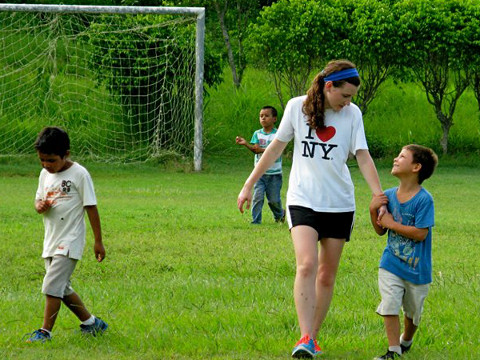 A high school girl from the United States walks off a soccer field, holding the hands of a young Guatemalan boy while on a mission trip in Zacapa,Guatemala (Credit: Brittany Kulick)