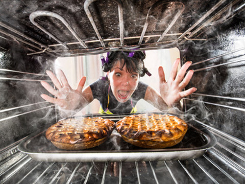 How to survive Thanksgiving concept: womans wearing apron screams as she reaches into her oven to retrieve two burning pies (Credit: Andrey Armyagov via Fotolia)