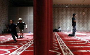 Children play behind a curtain to separate the men and women in a prayer hall at the Islamic Cultural Center of New York in the Manhattan borough of New York (Credit: Reuters/Lucas Jackson)