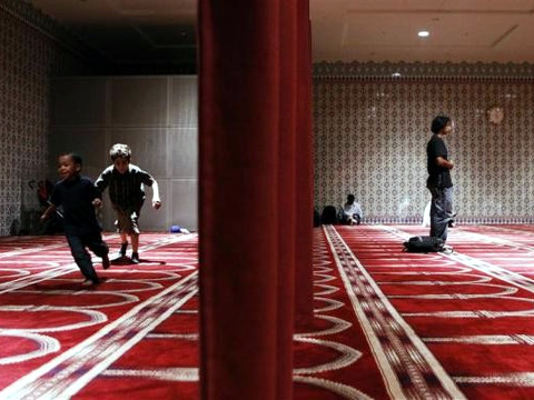 Children play behind a curtain to separate the men and women in a prayer hall at the Islamic Cultural Center of New York in the Manhattan borough of New York (Credit: Reuters/Lucas Jackson)