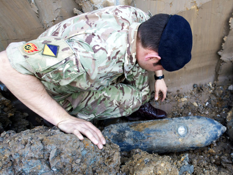 An army bomb disposal expert inspects an unexploded World War II 50-kilogram (110-pound) bomb, believed to have been dropped over London during German bombing raids in the early 1940s, which was discovered by workers at a construction site near Wembley Stadium, May 21, 2015 (Credit: Mod Crown/Royal Logistics Corps/Sargeant Rupert Frere)