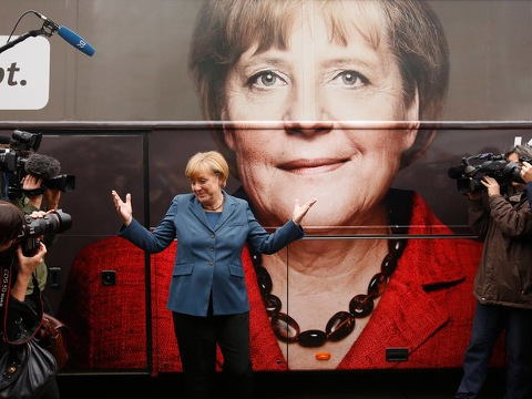 Chancellor Angela Merkel of Germany, who leads the center-right Christian Democratic Party, gestures for photographers in front of her election campaign tour bus before a meeting in Berlin, September 16, 2013 (Credit: Reuters/Fabrizio Bensch)